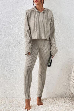 a woman standing on a rug wearing a sweater and pants
