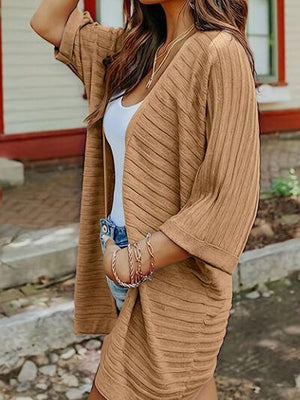 a woman wearing a tan cardigan and shorts