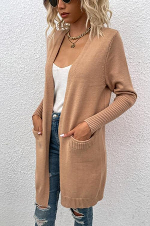 a woman wearing a tan cardigan sweater and ripped jeans