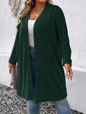 a woman standing in front of a wall wearing a green cardigan