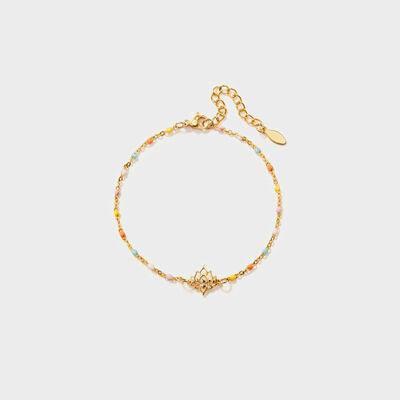 a gold bracelet with a heart charm on a white background