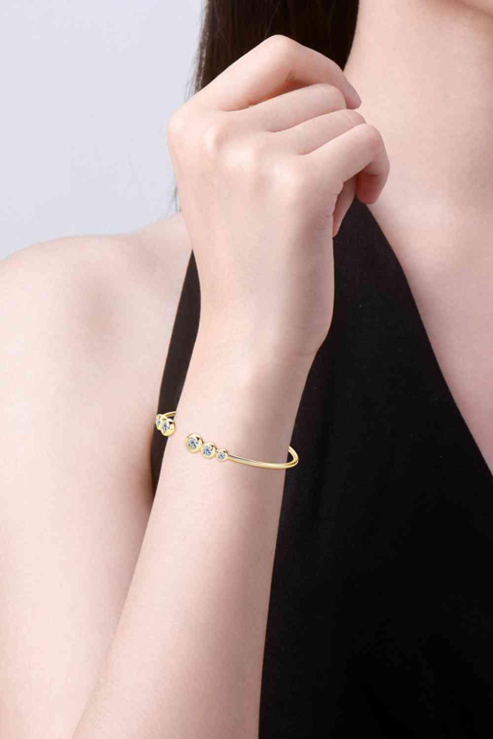 a woman wearing a gold bracelet with a diamond
