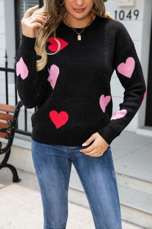 a woman wearing a black sweater with pink hearts on it