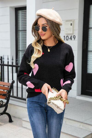 a woman wearing a black sweater with hearts on it