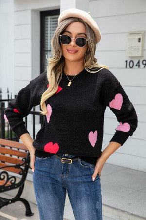 a woman wearing a black sweater with hearts on it