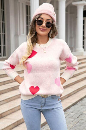 a woman wearing a pink sweater with hearts on it