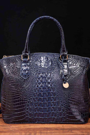 a blue alligator skin handbag sitting on top of a wooden table