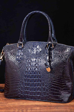 a black alligator skin handbag on a wooden table