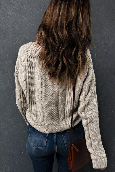 a woman with long hair wearing a sweater and jeans