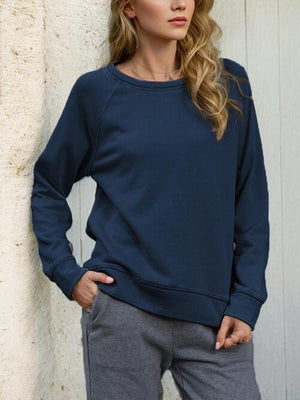 a woman standing next to a wall wearing a blue sweatshirt