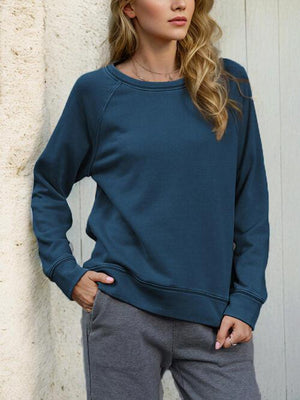a woman standing next to a wall wearing a blue sweatshirt