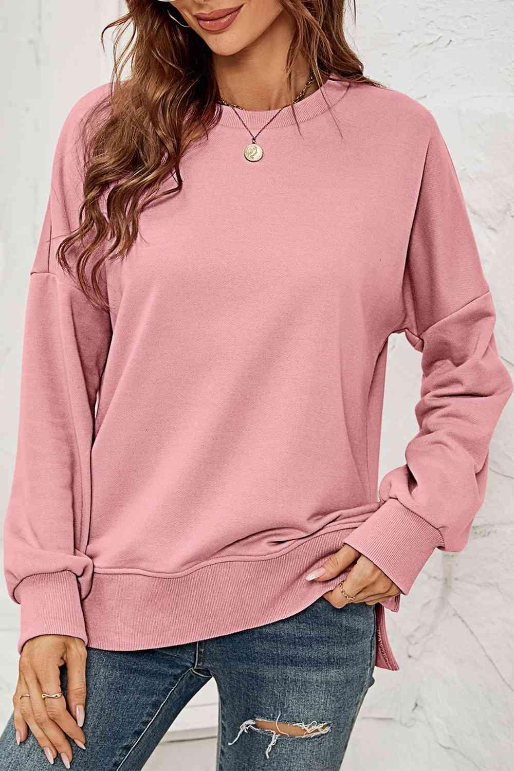 a woman wearing a pink sweatshirt and ripped jeans