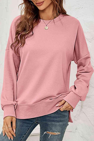 a woman wearing a pink sweatshirt and ripped jeans