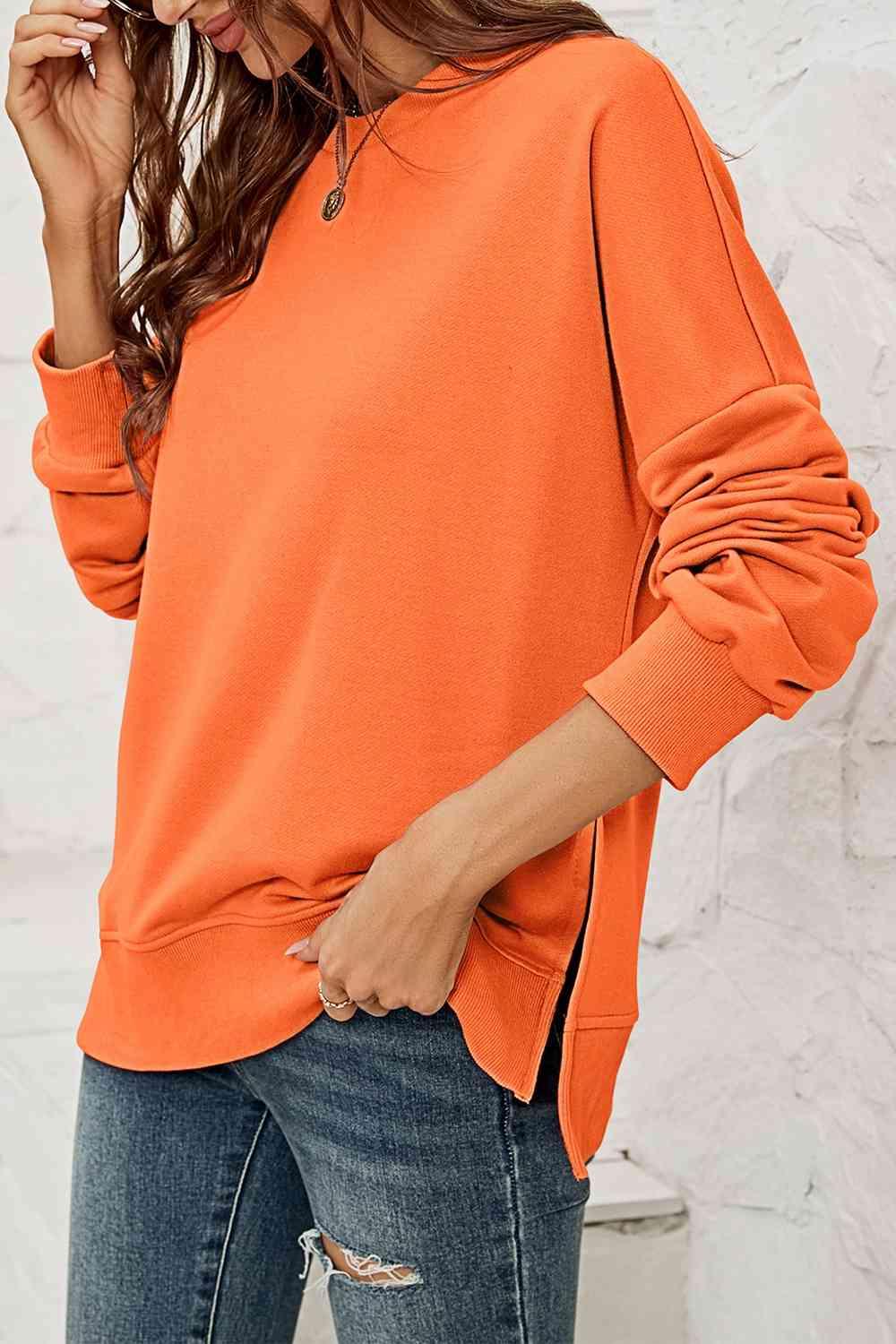 a woman wearing an orange sweatshirt and ripped jeans