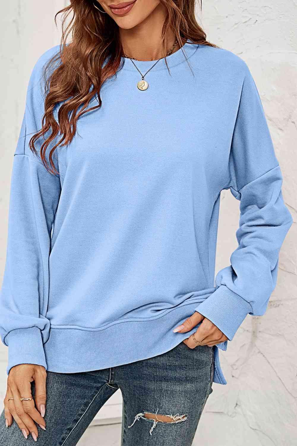 a woman wearing a blue sweatshirt and ripped jeans