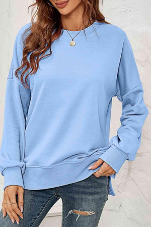 a woman wearing a blue sweatshirt and ripped jeans