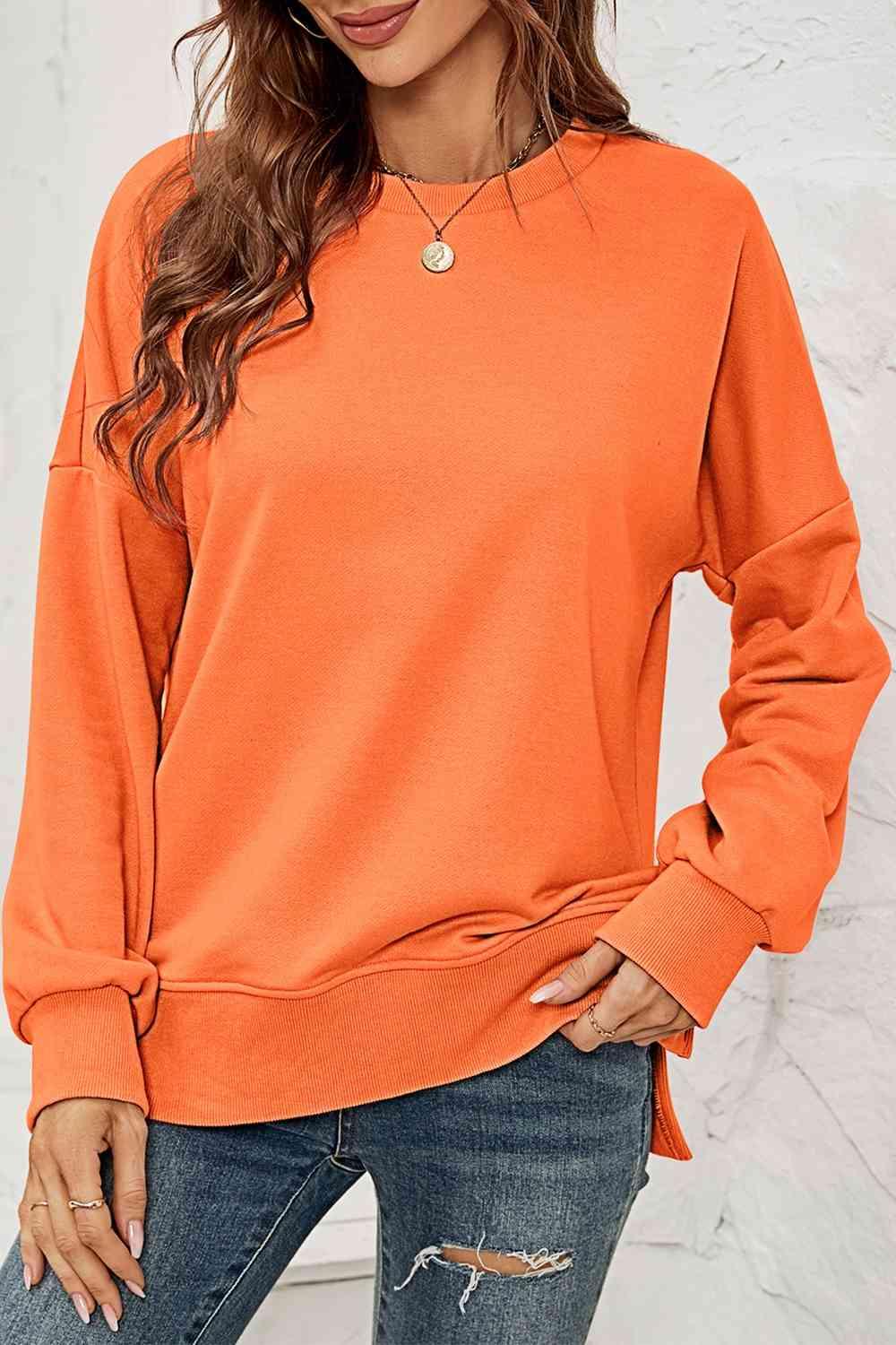 a woman wearing an orange sweatshirt and ripped jeans