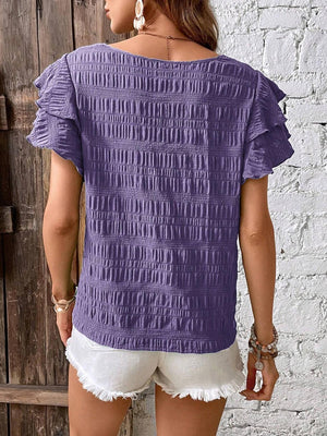 a woman wearing a purple top and white shorts