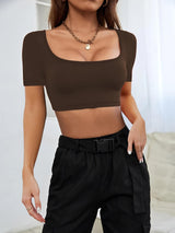a woman wearing a brown crop top and black pants