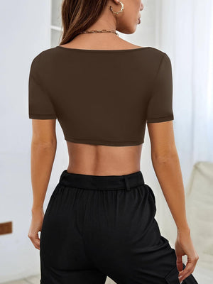 a woman wearing a brown crop top and black pants