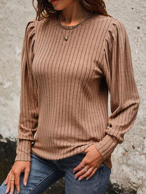 a woman wearing a brown sweater and jeans