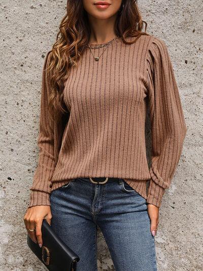a woman wearing a brown sweater and jeans