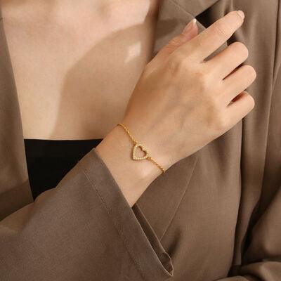 a woman wearing a gold bracelet with a heart on it