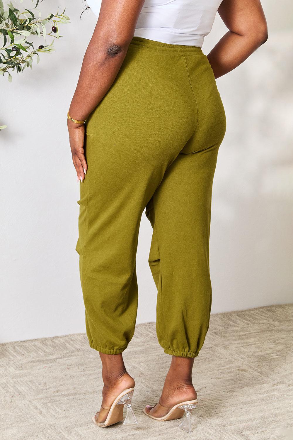 a woman in a white top and green pants