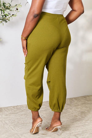 a woman in a white top and green pants