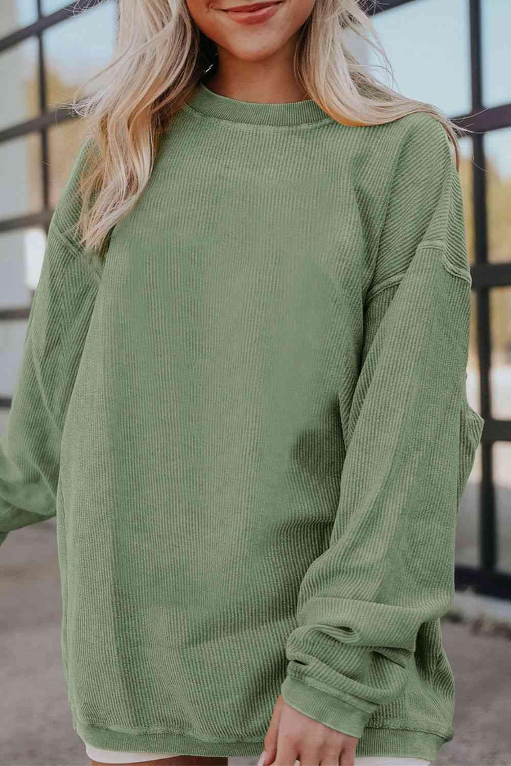 a woman wearing a green sweater and white shorts