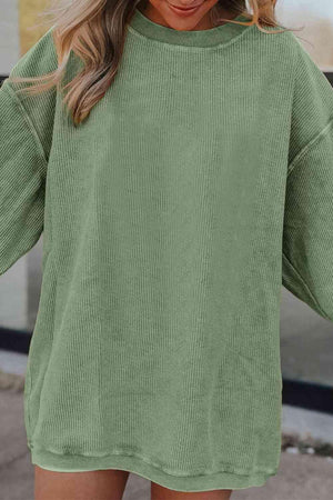 a woman wearing a green sweater and shorts