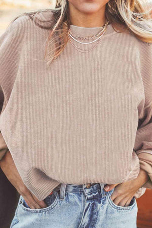 a woman wearing a tan sweater and jeans