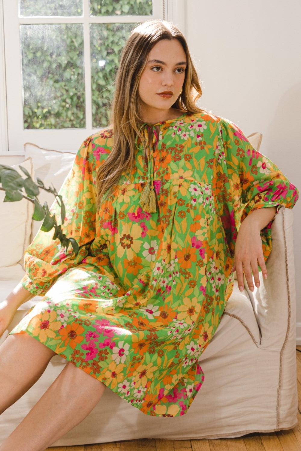 a woman sitting on a couch wearing a green floral dress