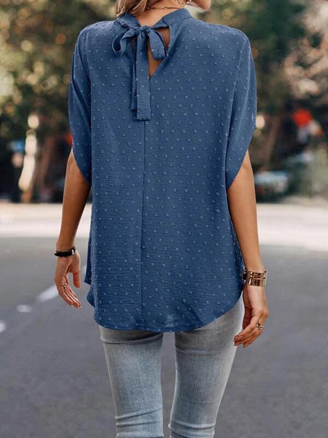 a woman walking down a street wearing a blue top