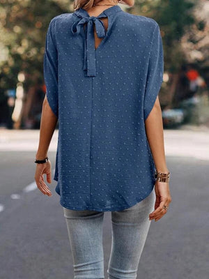 a woman walking down a street wearing a blue top