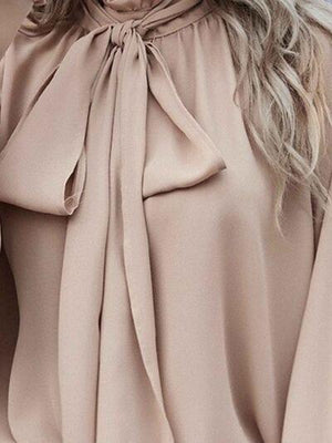 a woman with blonde hair wearing a beige blouse