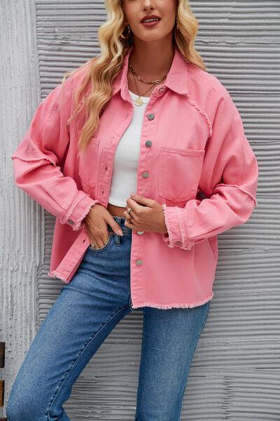 a woman in a pink jacket leaning against a wall