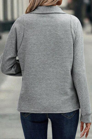 a woman walking down the street wearing a gray sweater