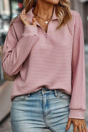 a woman wearing a pink sweater and jeans