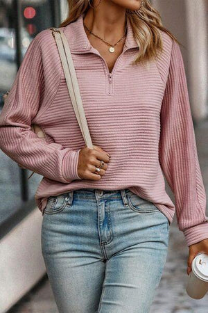a woman wearing a pink sweater and jeans