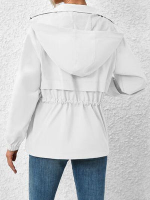 a woman wearing a white jacket and jeans