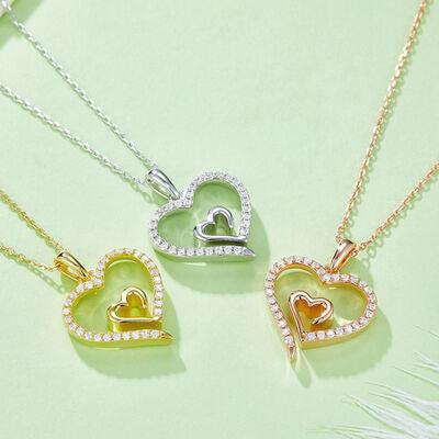 three heart shaped pendants on a green surface