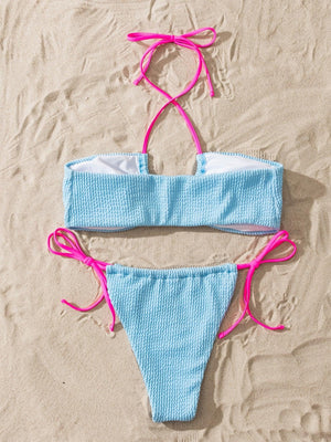 a blue and white bikini with pink ties on a beach