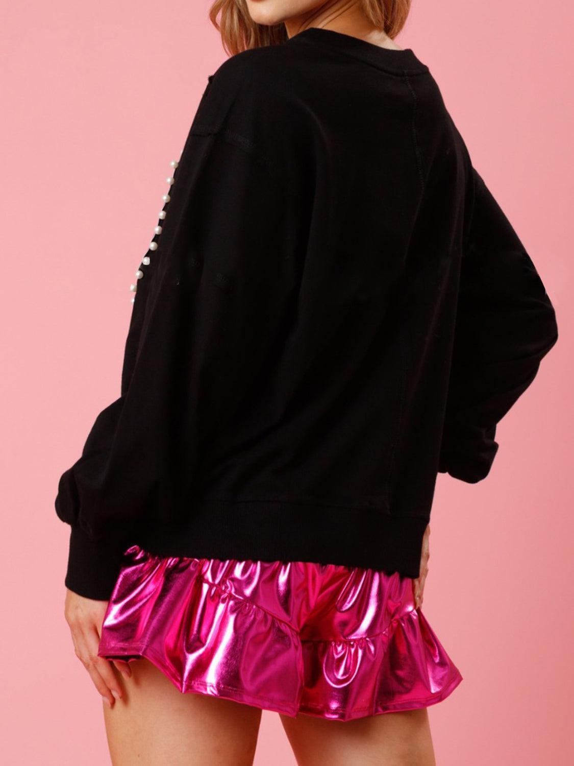 a woman wearing a black sweatshirt and pink skirt