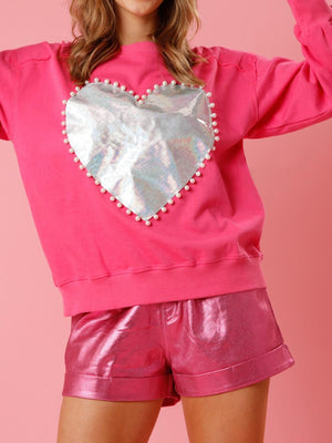 a woman wearing a pink sweatshirt with a heart on it