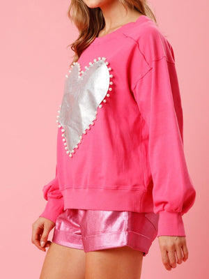 a woman wearing a pink sweatshirt with a heart on it