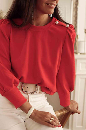 a woman wearing a red sweater and white pants