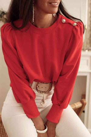 a woman wearing a red sweater and white pants