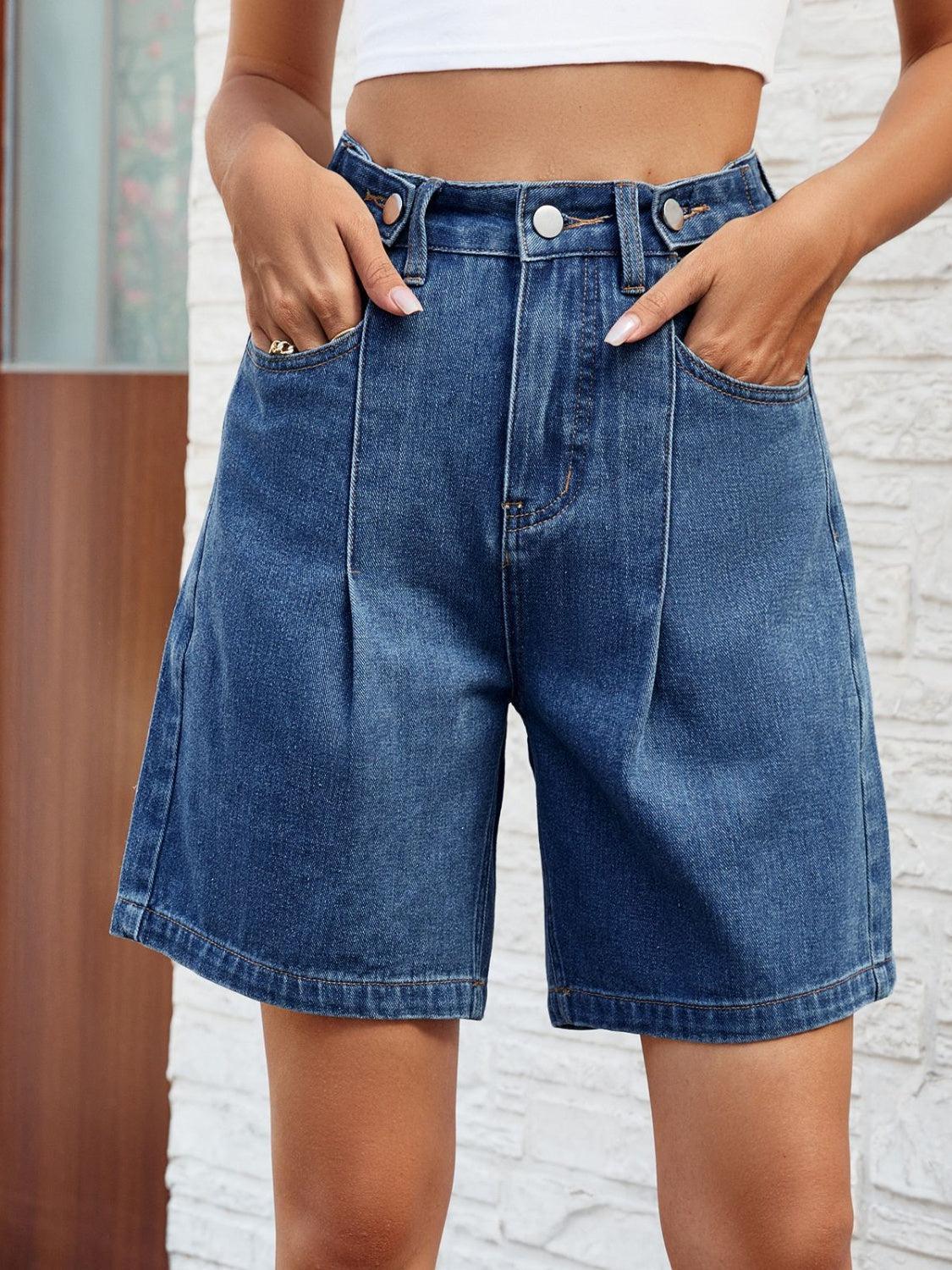 a woman wearing a white top and blue denim shorts