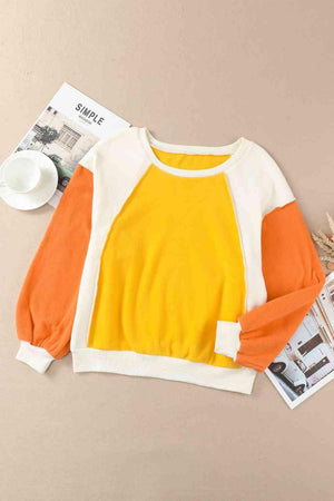 a yellow and white sweater with orange sleeves